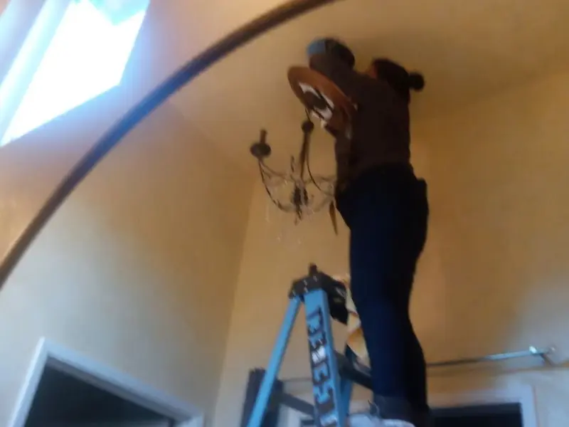 Electrician installing a chandelier in a Lexington residence